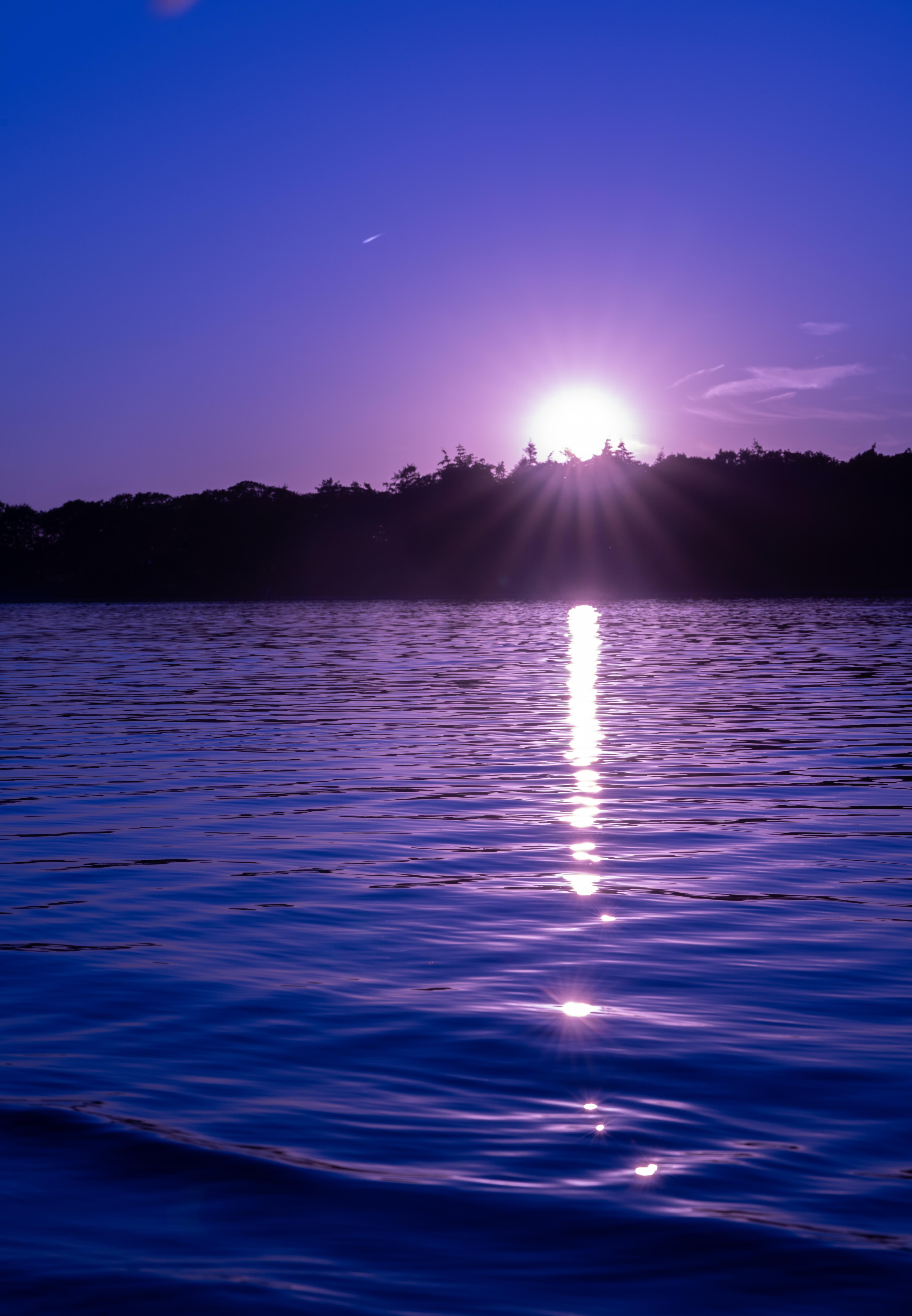 A setting sun over a rippling lake with a purple hue